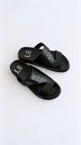 Sandalias de cuero color marrón con diseño asimétrico de tiras y plantilla anatómica. Tienen ajuste lateral con velcro y suela plana.