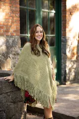 Poncho de lana merino color verde oliva, con diseño de tejido de punto grueso, corte asimétrico y flecos en el ruedo.