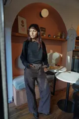 Remera negra de mangas largas con detalle de frunce en una manga y drapeado en el hombro.