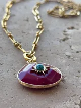 Cadena dorada con eslabones rectangulares y dije en forma de gota color borgoña con detalle de estrella turquesa en el centro.