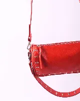 Bandolera de cuero natural color rojo, con diseño rectangular y detalles de tachas metálicas en los laterales y en la correa. Cuenta con cierre superior y dos asas desmontables.