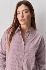 Camisa de calce relajado con diseño a rayas verticales, cuello clásico, mangas largas y cierre frontal con botones. Presenta bolsillos aplicados en el delantero.