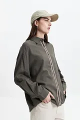 Camisa oversize color crema con detalles de puntilla roja en el frente.