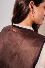 Chaleco sin mangas de corte al cuerpo, color negro con bordados florales en hilo contrastante. Presenta un diseño abierto con terminaciones reforzadas.