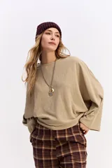 Blusa de corte relajado y fit holgado, con mangas largas amplias y textura sutil. Presenta un diseño minimalista con caída suave.