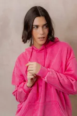 Canguro oversize fucsia con efecto washed, capucha con cordones ajustables al tono, bolsillo frontal tipo canguro y terminaciones de rib en puños y cintura.