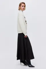 Buzo oversized color crema con cuello redondo acanalado. Presenta un estampado frontal en negro con el texto "VERMONT SKI CLUB Montpelier 1970" y un logo de montaña. Tiene hombros caídos y remates acanalados en puños y bajo.