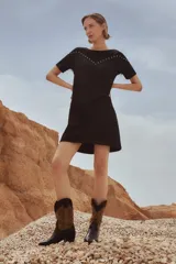 Vestido corto negro con cuello redondo, mangas cortas y detalle de flecos en el pecho.