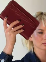 Billetera de cuero color bordó con cierre de cremallera y detalle de costuras en relieve. Interior con doce compartimentos para tarjetas y espacio para monedas y billetes.