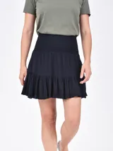 Falda corta de color negro, con cintura elástica tipo nido de abeja y ruedo con volado.