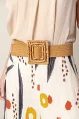 Cinturón elástico rústico de rafia color beige, con hebilla cuadrada de ratán trenzado.