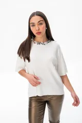 Remera blanca de viscosa con cuello redondo decorado con apliques plateados y mangas cortas amplias.