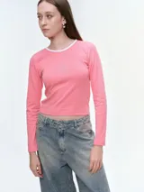 Remera de manga larga entallada, color rosado, con cuello redondo en contraste blanco y detalle de estrella bordada con brillos en el centro del pecho.