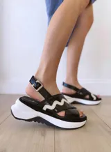 Sandalias negras de cuero con plataforma blanca y detalle de onda blanca en el empeine.