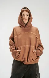 Hoodie oversize color beige con efecto batik, costuras expuestas y recortes estructurales. Presenta capucha amplia y bolsillo frontal tipo canguro.