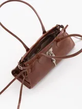 Cartera Kate de cuero vacuno diseñada para llevar al hombro, con cierre principal y bolsillo interno. Presenta aplique de candado y llavero tipo birkin en el frente, además de tiras laterales decorativas.