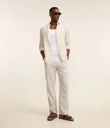 Pantalón de vestir de lino color beige, de corte recto, con bolsillos laterales y traseros. Se ajusta a la cintura con cinturón de cuero marrón.