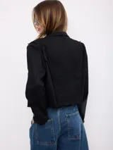 Chaqueta corta negra de gabardina con detalles de cordones decorativos bordados en el frente y bordes deshilachados.