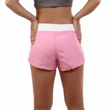Short deportivo para mujer color rosa vibrante, con cintura ancha elástica blanca y panel lateral blanco. Presenta el logo de Diadora en negro en la parte inferior frontal.