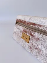 Billetera de cuero con textura rústica y acabado desgastado, presenta un diseño de solapa triangular con un detalle bordado en forma de espiga en el centro.