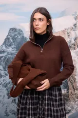 Buzo de tejido de punto color marrón chocolate, con cuello alto y cierre frontal parcial. Presenta mangas largas y un diseño de corte holgado.