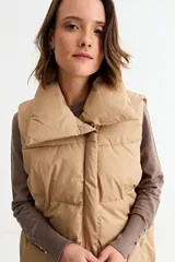 Chaleco puffer de corte holgado y diseño acolchado, con cuello alto y cierre frontal oculto. Presenta cordón ajustable en el ruedo inferior y bolsillos laterales.