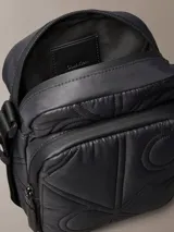 Cartera reporter Calvin Klein color negro, con diseño acolchado y pespuntes que forman el monograma de la marca. Cuenta con compartimento principal con cierre, bolsillo delantero con cremallera y correa ajustable para el hombro.