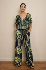 Enterito de jersey con capa superpuesta de tul estampado en tonos verdes, con escote en V, mangas cortas tipo capa y pantalón de corte recto y holgado.