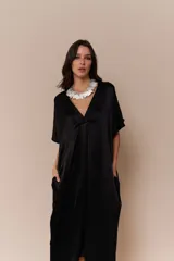 Vestido negro de corte midi, con escote en V y mangas cortas amplias. Presenta un cuello blanco con volados.
