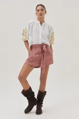 Camisa blanca de mezcla lino-algodón, con corte recto y mangas clásicas. Presenta un bordado floral en el hombro con distintas técnicas y canutillos.