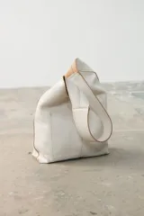 Mini tote de cuero agamuzado color blanco con acabado craquelado, diseño minimalista con asa ancha integrada, cierre con botón magnético y bolsillo interior.