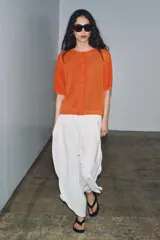 Chaqueta de punto de manga corta y cuello redondo en color verde, con cierre frontal de botones.