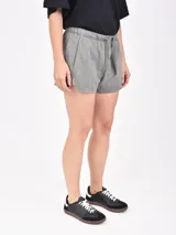 Short negro de tejido rústico, con cintura elástica con cordón de ajuste y bolsillos laterales.