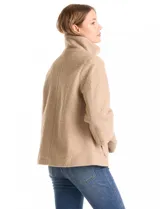Tapado de tejido boucle color verde oscuro, con silueta evasé y largo a la cadera. Presenta cuello alto envolvente, cierre frontal con botones a presión ocultos y bolsillos frontales de gran tamaño. Cuenta con mangas 3/4 de corte amplio y puños de tejido rib al tono que se extienden para cubrir las muñecas.