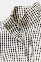 Chaqueta estilo bomber con estampado de cuadros vichy en blanco y negro, de cuello subido, manga larga y bolsillos delanteros de vivo. Cuenta con bajo abullonado y cierre frontal con cremallera oculta.