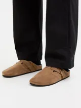 Zueco de gamuza color cognac, con puntera redonda, tira ajustable con hebilla, suela de corcho y base de goma.