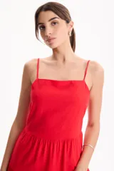 Vestido largo color blanco, confeccionado en lino, con tiras finas regulables, escote recto y falda amplia de corte acampanado con volados escalonados.