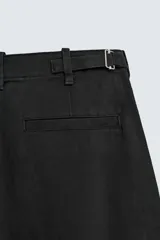 Pantalón de corte balloon fit y estilo relajado, confeccionado en tejido de algodón. Presenta pliegues frontales, cintura con trabillas, cierre frontal con cremallera y botón, bolsillos delanteros y bolsillos traseros de vivo.