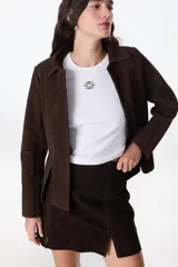 Chaqueta marrón de cuero vacuno descarne, con cuello camisero, corte entallado con pinzas y mangas sastre. No tiene botones.