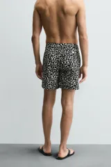Short de baño largo con estampado geométrico en tonos oscuros sobre fondo claro, cintura elástica ajustable con cordón y bolsillos laterales.