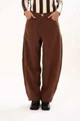 Pantalon de tiro medio con silueta curvada, mas ancha en la zona del muslo y la rodilla, con bolsillos laterales y cierre frontal con cremallera y boton.