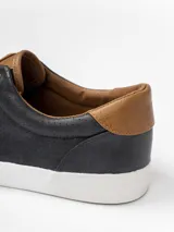 Champion de estilo urbano en color azul marino, con detalles en cuero sintético color suela en la lengüeta y el talón. Presenta perforaciones decorativas en los laterales y suela de goma blanca.