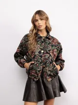 Campera tipo bomber con estampado floral estilo tapicería en tonos oscuros, con cuello clásico, cierre frontal con botones metálicos y bolsillos laterales.