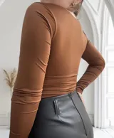 Body color marrón con escote cuadrado, mangas largas y detalle de hebillas doradas en el frente.