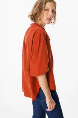 Camisa de pana color verde oliva, con cuello mao, cierre frontal de botones y mangas largas abullonadas con puños elásticos.