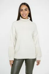 Polerón de cuello alto en color crudo, confeccionado en tejido de punto con mangas largas que presentan puños de textura afelpada y diseño holgado.