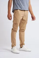 Pantalón cargo de corte slim, color beige, con cierre y botón frontal, bolsillos laterales tipo cargo y terminación recta sin puños.