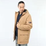 Parka ligera color beige con capucha ajustable, cierre frontal con cremallera y parche decorativo con texto en la manga.