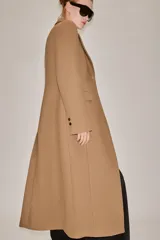 Abrigo largo entallado de Zara Woman Collection, confeccionado en mezcla de lana color tostado. Presenta cuello con solapa de muesca, mangas largas, bolsillos con solapa en el frente, forro interior y cierre frontal de dos botones oscuros.