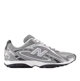 Championes urbanos New Balance modelo 204, color gris con detalles en blanco y negro. Confeccionados en malla técnica y refuerzos sintéticos, presentan el logo lateral característico de la marca y suela de goma con relieve.